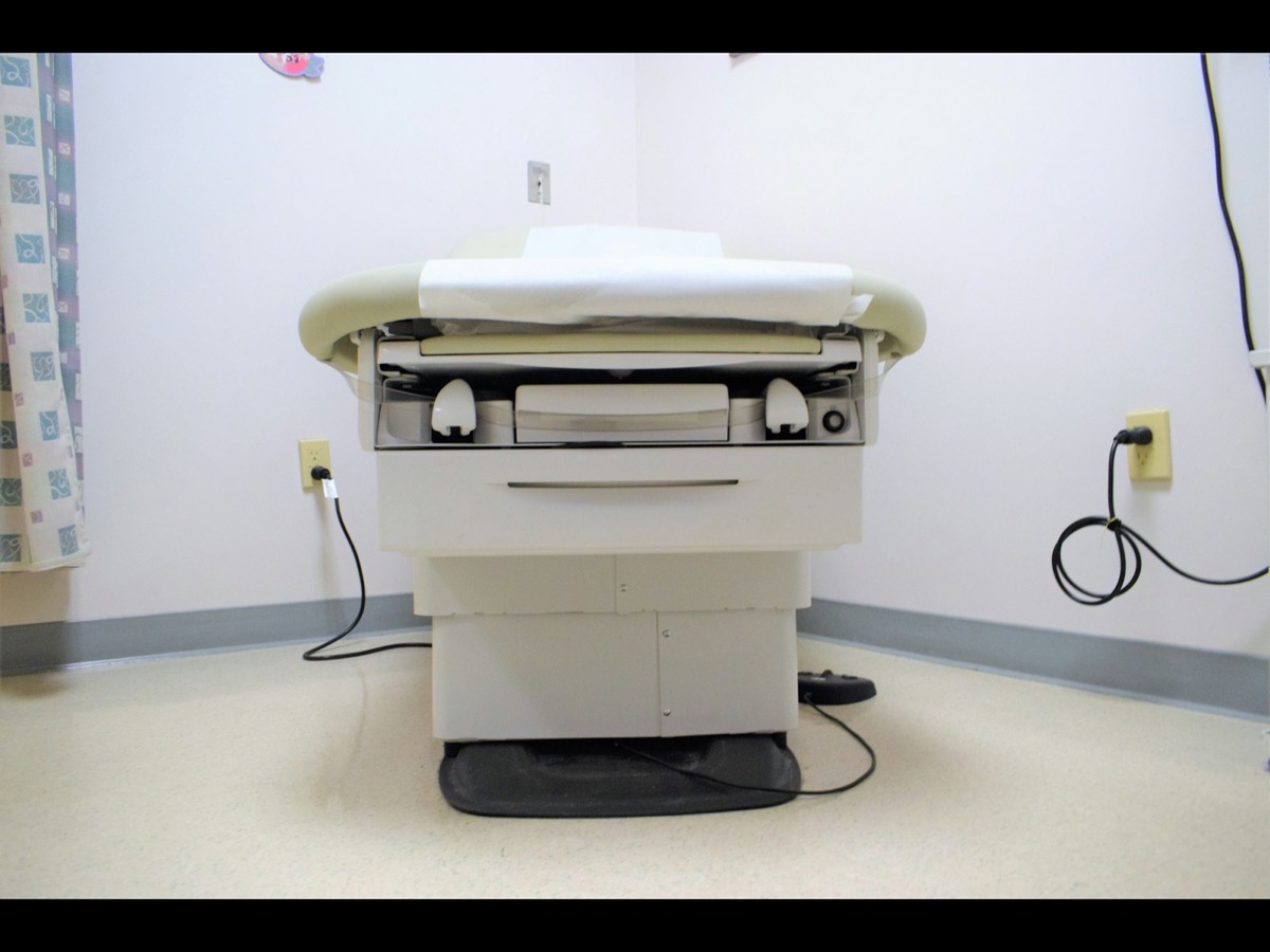 An empty clinical examination room with an exam table.